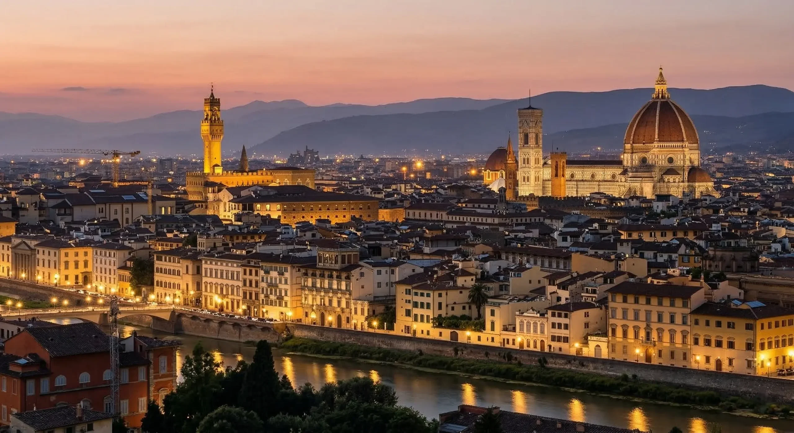 Florence panoramic skyline view at dusk with illuminated Duomo, Campanile, Palazzo Vecchio, and Ponte Vecchio.